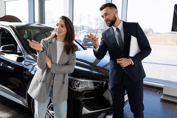Woman in car dealership talks to salesman