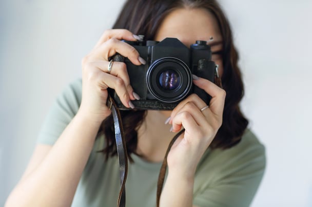 Woman looking through lens view of camera to take a photo. 