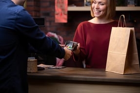A woman behind a cash register helping a customer check out and pay for their purchase.