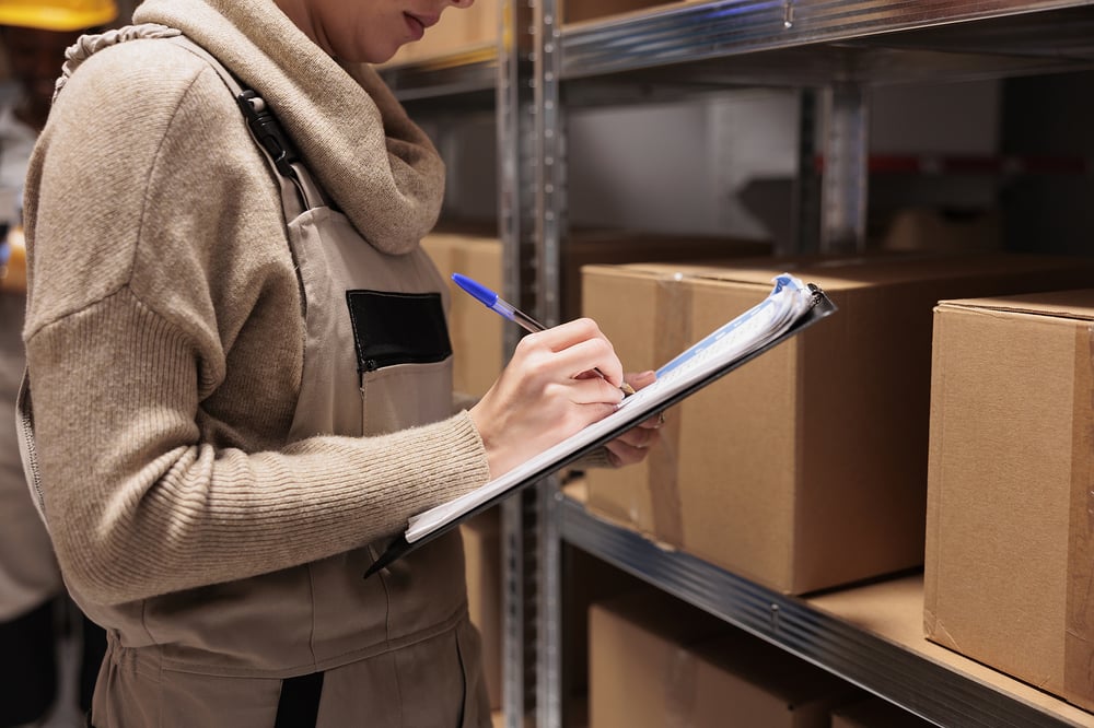 Woman writing business inventory on a clipboard
